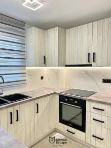 a kitchen with white cabinets and a black oven at Matouli Escape in Filótion +29 photos