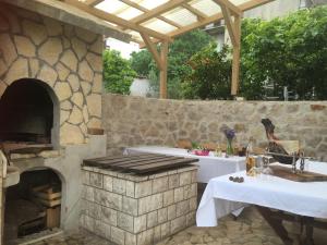una cocina al aire libre con horno de piedra y mesas. en Apartments Lucija-Klara, en Brodarica