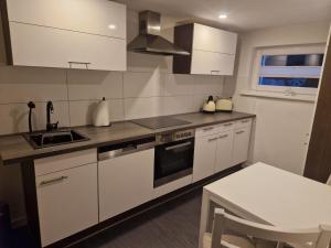 a kitchen with white cabinets and a sink and a table at Leuchters Unterkunft in Bad Doberan