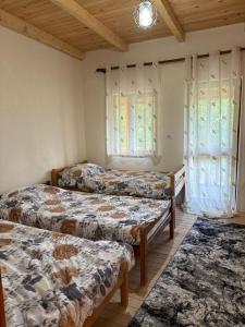 two beds in a room with windows and a rug at Lekbibaj view in Tropojë +17 photos