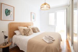 a white bedroom with a bed with towels on it at AG Piso Porto de Mar Malpica, a 250m de la playa in Malpica