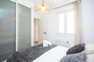 a bedroom with a white bed and a chandelier at AG Piso Porto de Mar Malpica, a 250m de la playa in Malpica