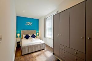 a bedroom with a bed and a blue wall at Imperial Middlesex Street Apartments in London