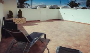 un patio con 2 sedie e una parete bianca di Casa Min26 a Caleta De Fuste