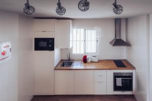 una piccola cucina con armadi bianchi e lavandino di Casa Min26 a Caleta De Fuste