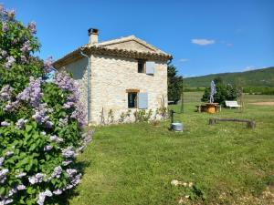 a stone house in a field with purple flowers at Le grangeon des Hermas in Sault-de-Vaucluse
