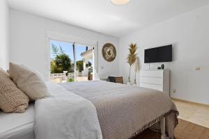 a white bedroom with a bed and a television at Villa Roco Marbella private pool and sea view in Marbella