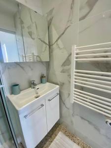 a white bathroom with a sink and a mirror at Villa Salve Maria, proche plage et centre ville, ménage et draps compris in Arcachon
