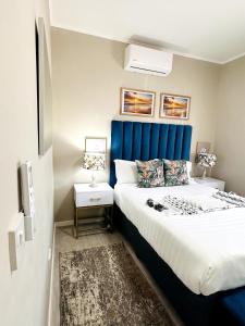 a bedroom with a large bed with a blue headboard at PrimVilla Apartment in Gaborone