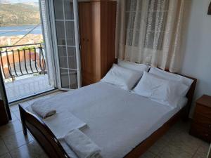 a bed with white sheets and pillows in a room with a window at ELENA SEAVIEW house in Argostoli