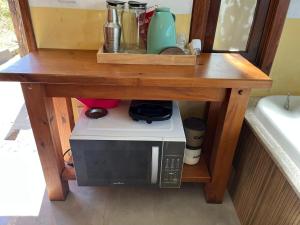 a microwave under a wooden table with a counter top at Chalé Flor de Maracujá in Lavras Novas