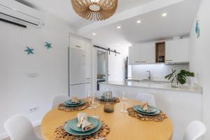a kitchen and dining room with a wooden table and chairs at Sunrise House Oliva Nova Beach & MET Apartment in Oliva