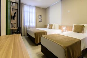 a hotel room with two beds and a table at Hotel Santa Cruz in Santa Cruz do Sul