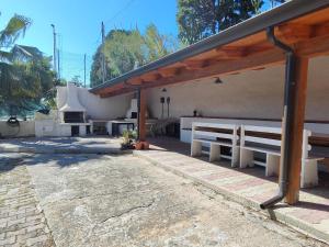 a pavilion with white benches in front of a building at Michela's house in Capo Vaticano