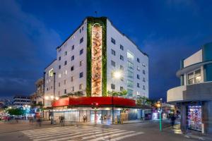 a tall white building with a lit up facade at Hotel Presidente in San José