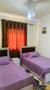 two beds in a room with purple and orange curtains at شاليه لاسرينا العين السخنه in Ain Sokhna