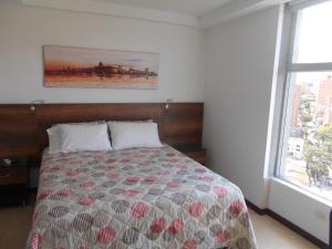 a bedroom with a bed and a painting on the wall at Laureles penthouse, jacuzzi-rooftop fun in the sun in Medellín