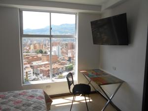 a bedroom with a desk and a large window at Laureles penthouse, jacuzzi-rooftop fun in the sun in Medellín