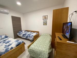 a small room with two beds and a television at MaGa House in Catania