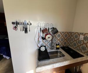 a kitchen counter with a sink and utensils at Chalé Flor da Fortuna in Lavras Novas +1 photo