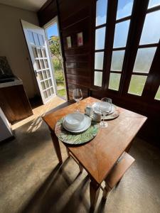a wooden table with plates and wine glasses on it at Chalé Flor da Fortuna in Lavras Novas