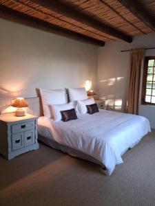 a bedroom with a large white bed with a night stand at Schalkenbosch Heritage Cottages in Tulbagh +55 photos