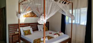 a bedroom with a canopy bed with white curtains at Long Beach Resort, Nosy Be in Nosy Be +86 photos