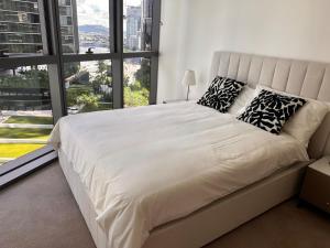 Un dormitorio con una cama grande con una ventana grande. en Queens Wharf TWO Bedrooms Apt, en Brisbane