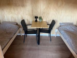 a table and chairs in a room with two beds at Hærvejshallen Hytte 3 in Bække +10 photos