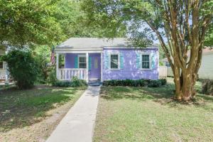a purple house with a tree in a yard at The Little Sandy Flamingo in Gulfport