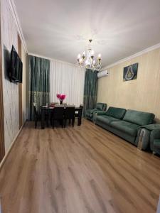 a living room with a table and a green couch at Sumqayıt Bulvar in Sumqayıt