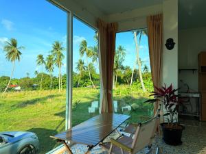 a table and chairs in front of a window with palm trees at Samui Retreat w Garden Seaview in Ban Nong Chaeng