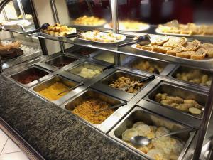a buffet line with many trays of food at Pousada Central in Feira de Santana