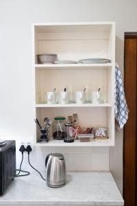 a kitchen shelf with dishes and utensils at Archers Guest House in Patentie