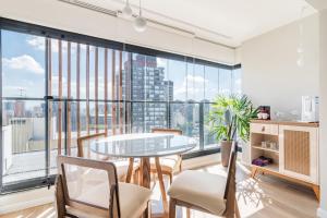 a dining room with a table and chairs and a large window at 360 Soma Perdizes in Sao Paulo