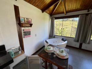 a bathroom with a tub and a table and a sink at Chalé Lírio do Campo in Lavras Novas