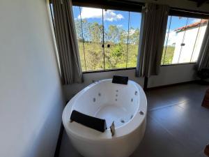 a large white bath tub in a room with large windows at Chalé Lírio do Campo in Lavras Novas