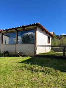 a small house with large windows in a yard at Chalé Lírio do Campo in Lavras Novas