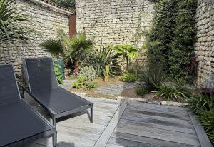 patio z 2 krzesłami i ceglaną ścianą w obiekcie La Brijolie 450m de la plage La Biroire w mieście Saint-Pierre-dʼOléron