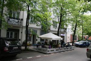 personas sentadas en una mesa bajo un paraguas en una calle en Smulikowskiego 9, en Varsovia