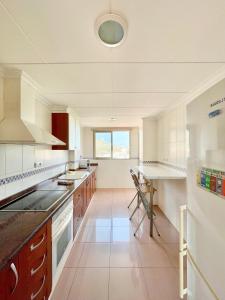 a large kitchen with white appliances and a window at Atico luminoso en Cullera centro. in Cullera