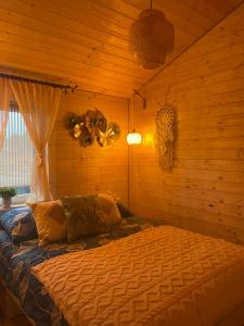 a bedroom with a bed in a wooden room at Całoroczny "Domeczek na zielonej łące" - w stylu boho in Nowęcin