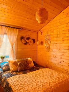 a bedroom with a bed in a wooden room at Całoroczny "Domeczek na zielonej łące" - w stylu boho in Nowęcin