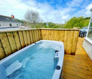 a hot tub on a deck with a wooden fence at Mary Cottage, Braunton, Devon in Braunton