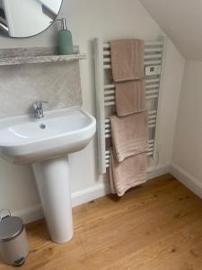 un bagno con lavandino, specchio e asciugamani di Pinabre Rose Cottage a Plouguenast Langast