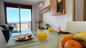 a kitchen with a table with fruit and orange juice at Coral beach in Peñíscola +28 photos
