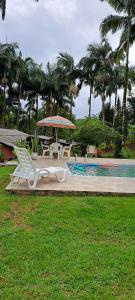 a pool with a table and chairs and an umbrella at Chácara gratidão a Deus in Morretes