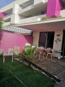 a pink building with chairs and a table on a patio at appartement 2 pieces avec parking ds résidence in Palavas-les-Flots