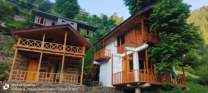 a building with wooden balconies next to a mountain at The mysteryworld a-wooden tree cottage jibhi in Banjār