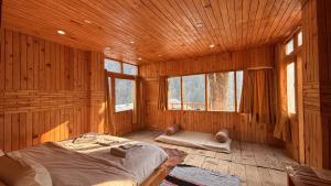 a bedroom with a bed in a wooden room with windows at The mysteryworld a-wooden tree cottage jibhi in Banjār +16 photos